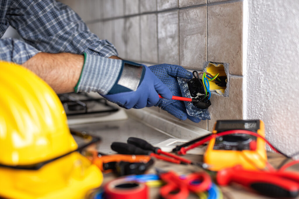 Electrician at work with screwdriver fixes the cable in the sockets of a residential electrical system. Construction industry.